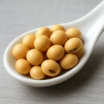 깨끗한 흰색 식기 위에 윤기가 흐르는 신선한 노란색 대두가 담겨 있습니다.