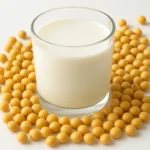 신선한 콩으로 만든 뽀얀 두유가 담긴 유리잔과 건강한 식물성 영양을 상징하는 모습입니다.