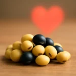 혈관 건강과 생명력을 상징하는 붉은 하트 배경 앞에 놓인 신선한 콩입니다.