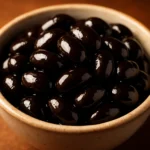 도자기 그릇에 윤기가 흐르며 부드럽게 익은 검은콩 조림이 정갈하게 담겨 있습니다.