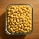 주방 조리대 위 투명한 유리 용기에 신선하게 삶은 콩이 깔끔하게 담겨 있는 모습입니다.