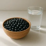 하체 부종 완화와 체내 수분 조절에 도움을 줄 수 있는 신선한 검은콩과 물 한 잔의 모습입니다.
